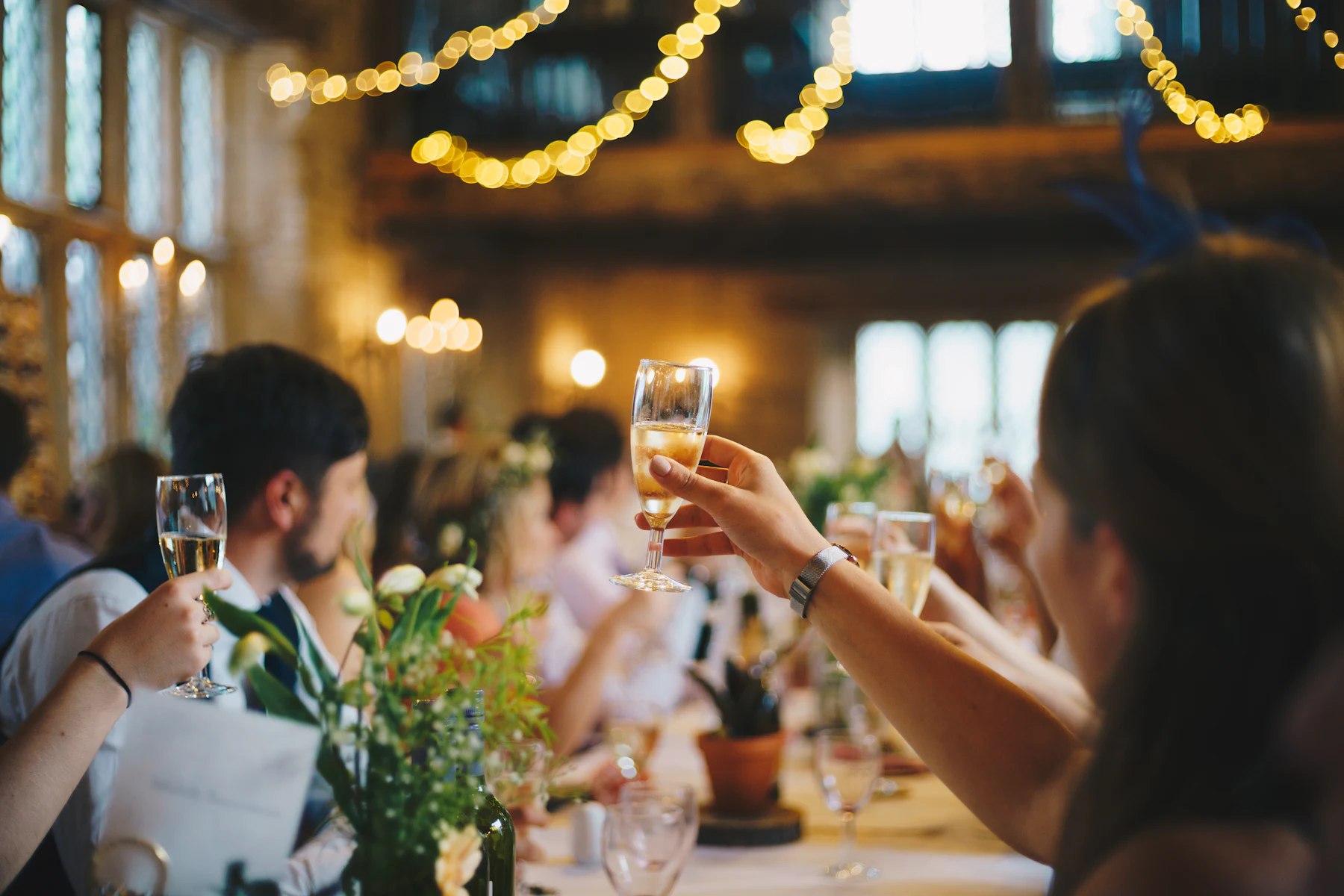 Glasses raised beneath string lights at a terrace supper, the season in full swing