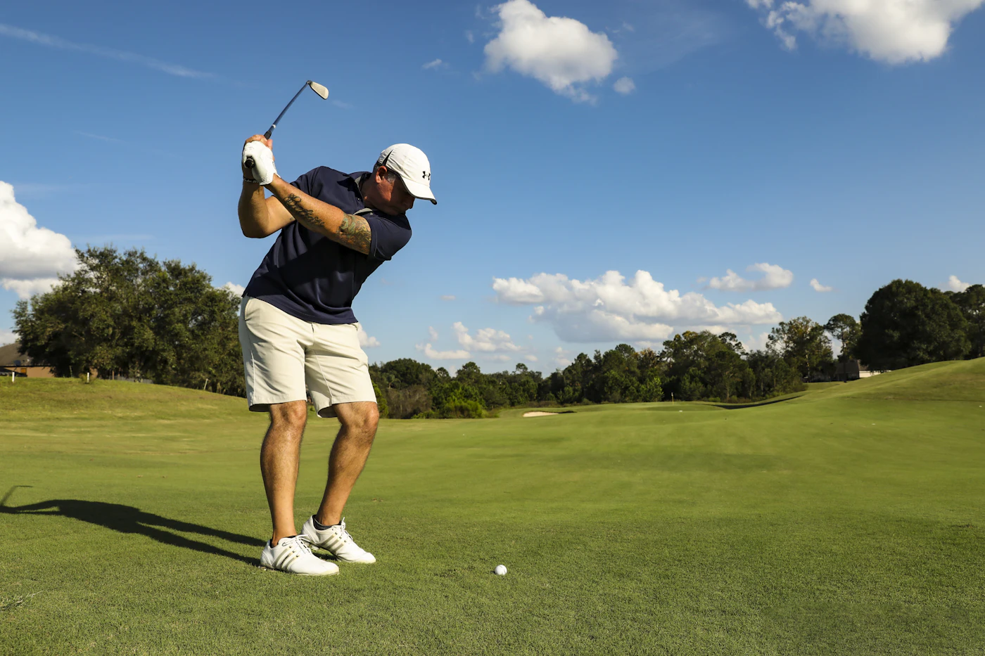 A member at the top of the backswing on the sixteenth tee, fairway falling away ahead
